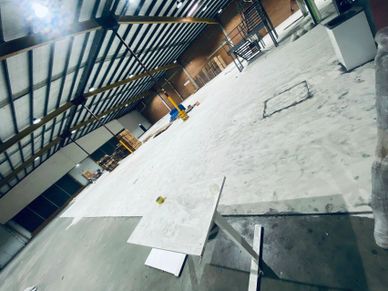 An empty industrial warehouse with a white table and scattered items on the floor.