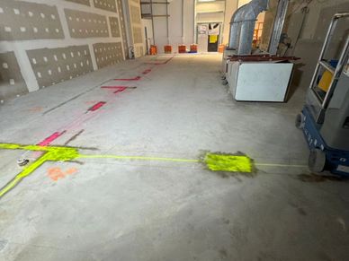 Concrete floor with neon yellow and pink markings in an unfinished building.