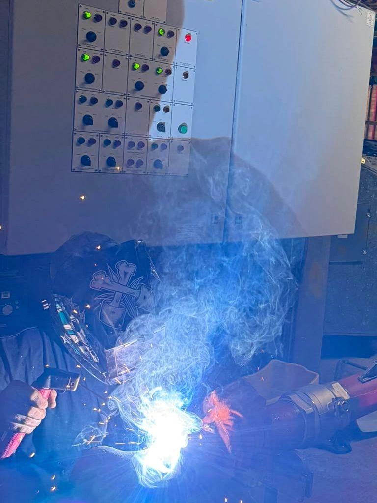 Person welding metal, sparks and smoke visible.