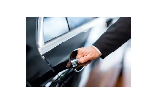 "A professional chauffeur in a sleek suit prepares to open the door for a client