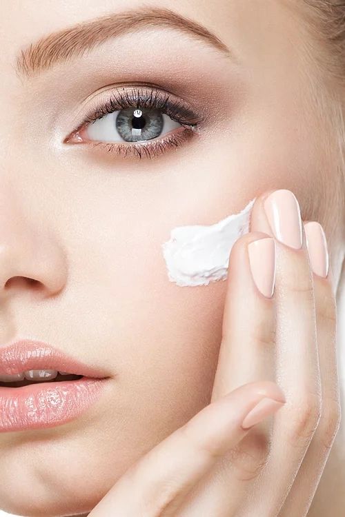 Woman applying cream on facial skin