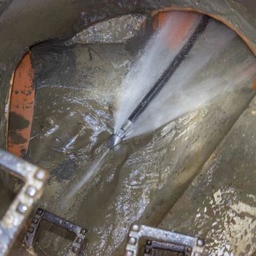 High-pressure water jet cleaning inside a large pipe or tunnel.