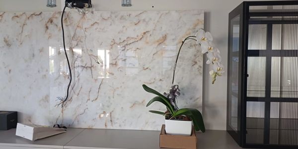 A white orchid plant in a pot on a desk with marble wall backdrop.