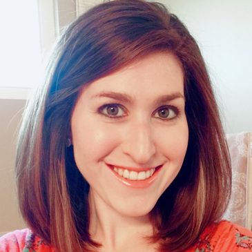 Close up image of a girl with brown hairs smiling at the camera