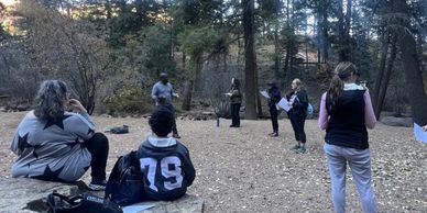 Group of people outdoors participating in an activity in the woods.