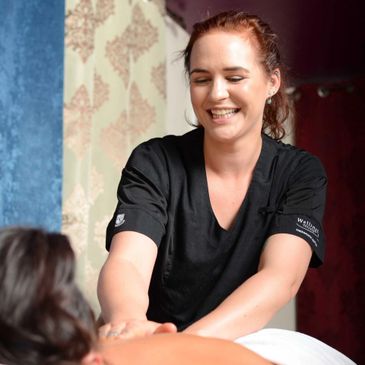 A smiling masseuse giving a massage to a client.