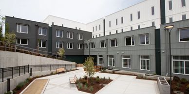 Modern gray and white building surrounding a landscaped courtyard with benches.