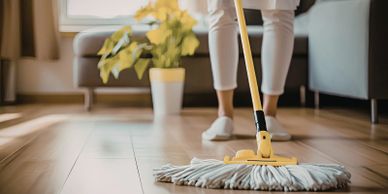 Person mopping a wooden floor in a cozy living room.