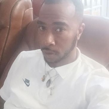 Man sitting on a couch wearing a white Nike shirt.