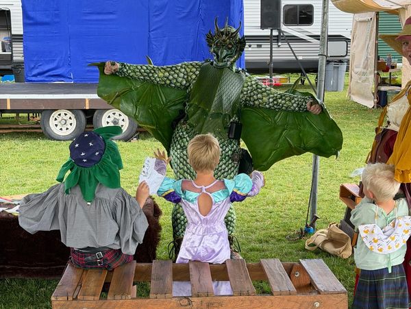 Children in costumes facing a person dressed as a dragon.