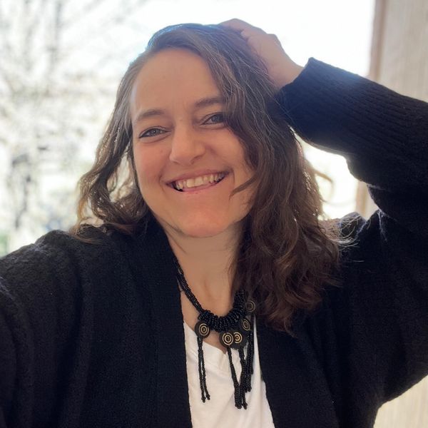 Smiling woman with wavy hair and a black necklace.