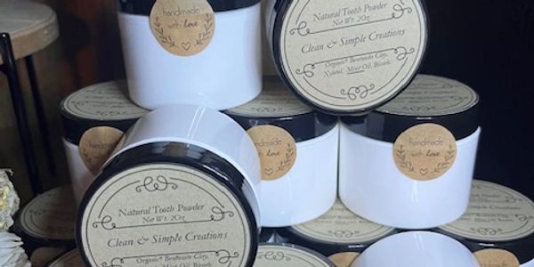 Stacked jars of natural tooth powder with handmade labels on a wooden shelf.