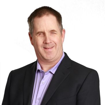 Smiling man with brown hair wearing purple shirt and blazer