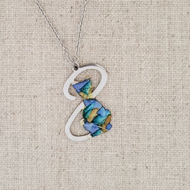 Silver cat pendant with colorful inlay on a chain.