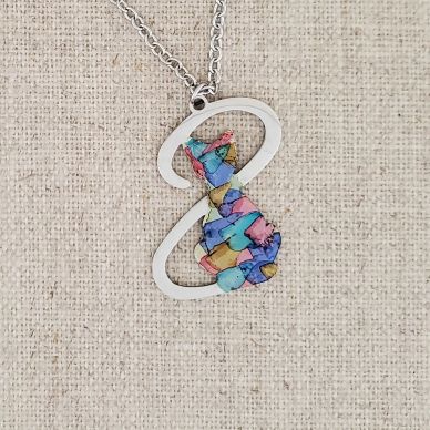 Colorful cat pendant necklace on fabric background.