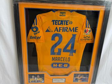 Framed yellow soccer jersey with the number 24 and sponsor logos.