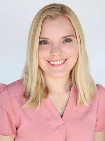 Smiling woman with blonde hair wearing a pink top.