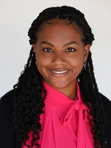 Smiling woman with braided hair and bright pink blouse.