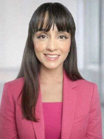 Smiling woman in a pink blazer.