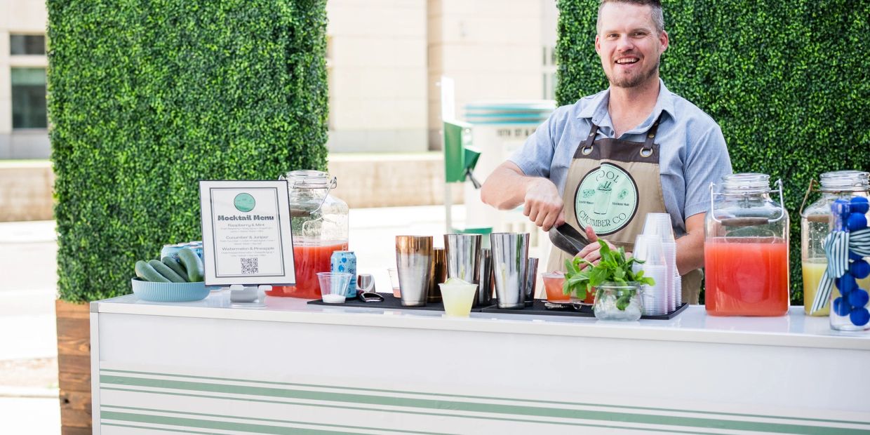 Man serving drinks at a mocktail bar outdoors.