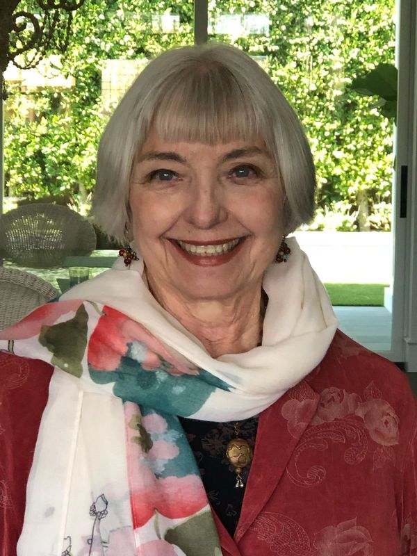 Smiling elderly woman with white hair and a colorful scarf.