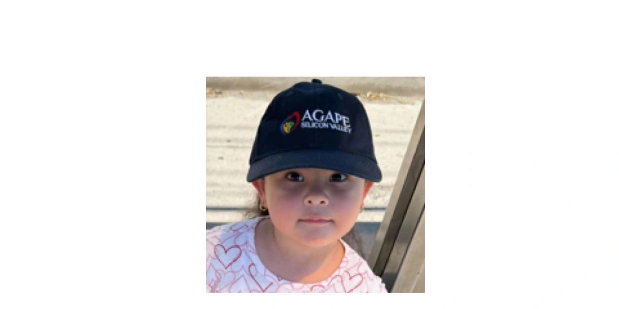 Young child wearing a black cap with 'Agape Silicon Valley' logo.
