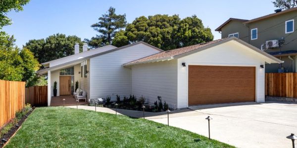 Modern single-story house with a wooden garage door and a manicured lawn.