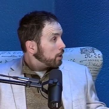Man speaking into microphone during a podcast or interview.
