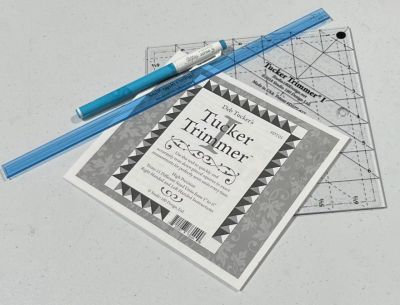 Tucker Trimmer quilting ruler with pen and blue ruler.