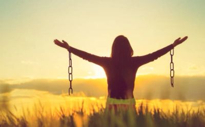 Silhouette of person with broken chains at sunset.