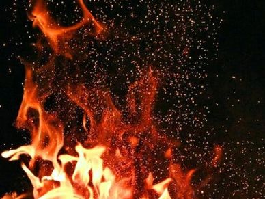 Bright orange flames with sparks against a dark background.