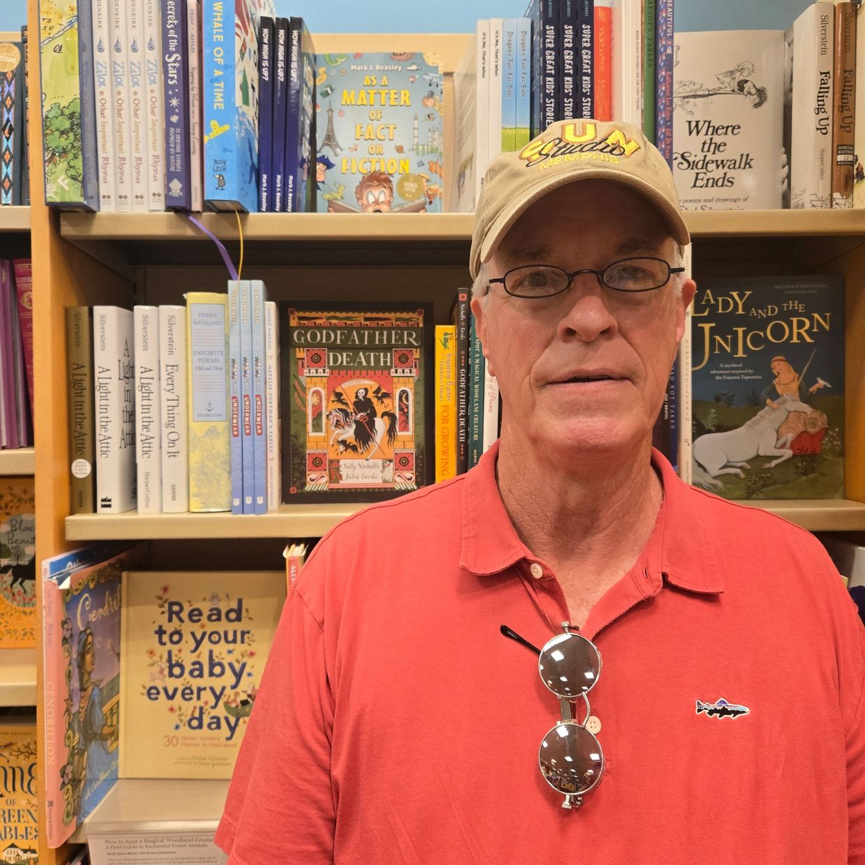 Man in red shirt and beige cap in bookstore.