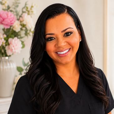 Smiling woman with long black hair in black scrubs.