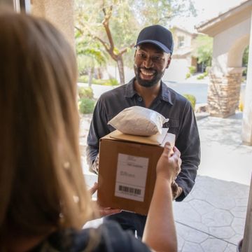 Delivery man handing packages to a smiling woman at her doorstep.