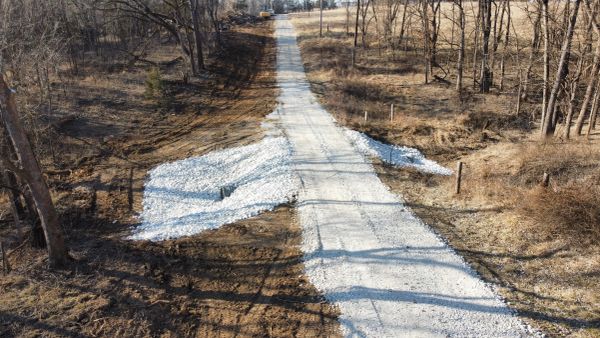 Gravel driveway with stone arrows pointing left and right in a rural area.