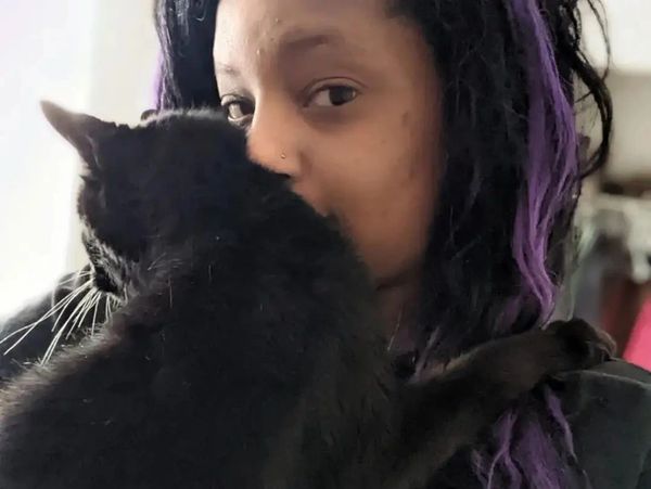 Person holding a black cat close to their face.