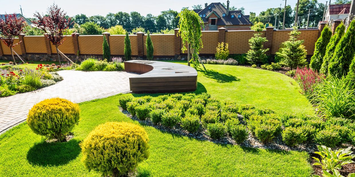 Landscape design that looks like it is in someones back yard with a wooden flat bench in the middle
