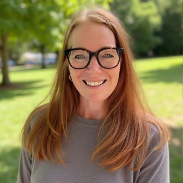 Smiling woman with glasses outdoors on a sunny day.