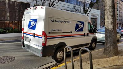USPS delivery van parked on a city street.