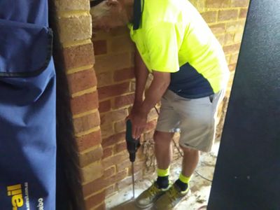 Drilling holes in concrete to inject termite chemical