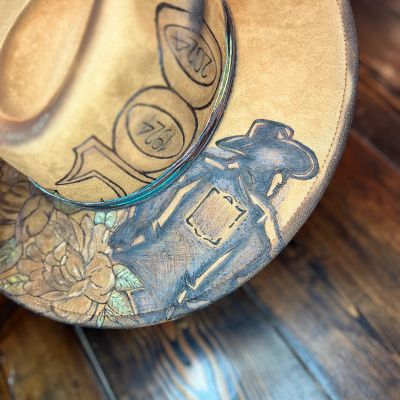 A tan cowboy hat with detailed painted artwork.