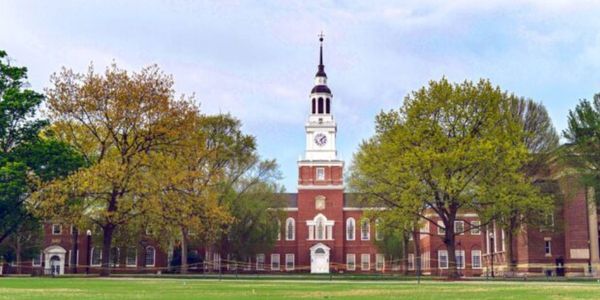 Historic red-brick building with a clock tower and surrounding trees.