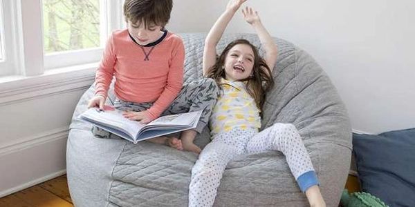 um menino e uma menina descansando em cima do puf de pérolas de isopor