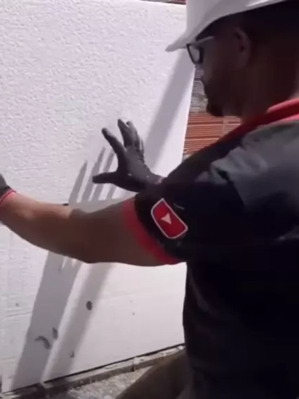Homem aplicando isopor na parede para fazer isolamento térmico.