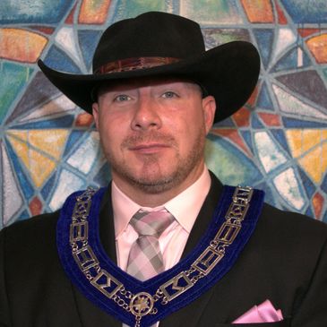 Man in a cowboy hat with a ceremonial chain.