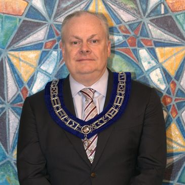Man wearing a ceremonial chain and suit.