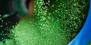 Close-up of green plastic pellets being poured from a container.
