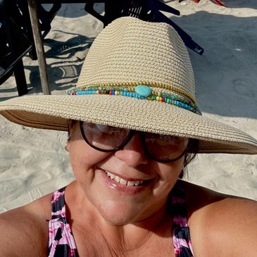 Awoman in a hat at her happy place, a sandy beach in Mexico.