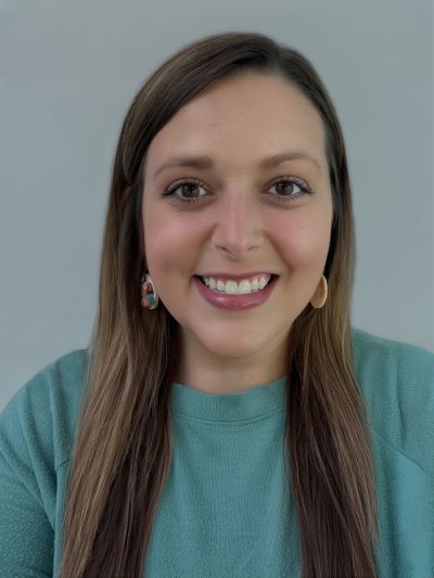 Smiling woman with long hair wearing teal top.
