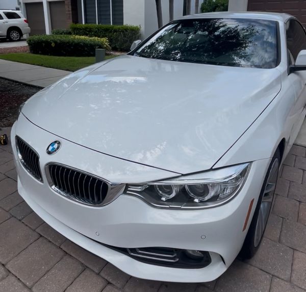 White BMW car parked on a residential driveway under natural daylight.